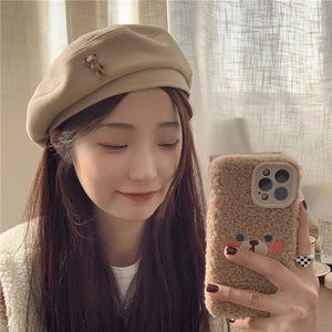 Detail view of khaki wool beret featuring a 3D teddy bear doll and soft autumn texture