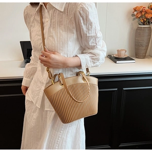 Detail view of light brown pleated PU leather bag with gold rings and shoulder strap