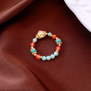 Close-up of vintage beaded ring featuring a golden fox head with agate and turquoise beads