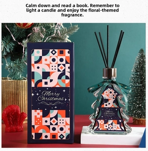 Detail of Christmas tree shaped diffuser bottle and navy gift box with festive decor