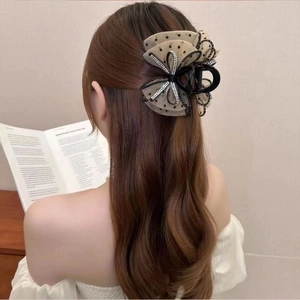 Detail view of elegant mesh hair claw clip with sparkling rhinestones and bow design.