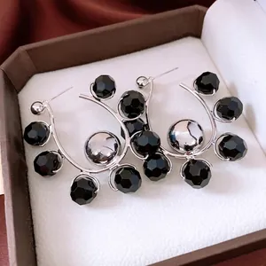Fashionable silver-tone half-hoop earrings with faceted black beads and a polished center ball