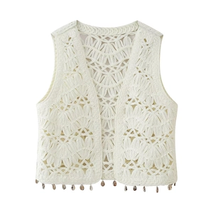 Detail of white crochet vest featuring shell charms and hollow-out knit patterns