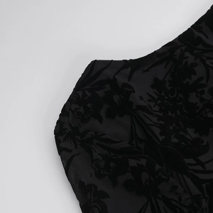 Close-up detail of black floral flocked pattern on sheer mesh fabric of the dress
