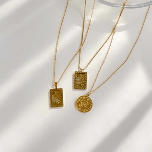 Detailed view of three vintage gold sun medallion necklaces with embossed sunburst designs