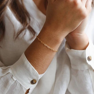 Detaillierte Nahaufnahme eines minimalistischen goldenen Büroklammer-Armbands am Handgelenk