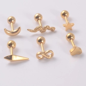Macro shot of gold-plated stud earrings in moon, star, heart and wing shapes