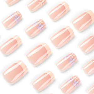 Short yellow French press-on nails with purple floral patterns on a nude pink base