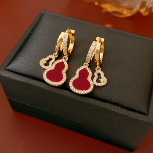 Detail of gold-plated hollow gourd earrings with red stones and sparkling zircons