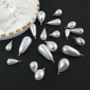 Macro detail of drop-shaped faux pearl pendants with gold-plated metal loops for DIY jewelry