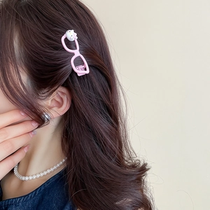 Detailed view of pink glasses-shaped hair clip with cartoon cat on brunette hair