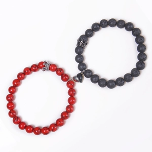 Detail of red and black magnetic couple bracelets with heart clasp and crown charms