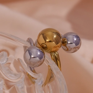 Macro shot of 18K gold and silver spheres on adjustable ring placed on glass rim