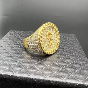 Iced out gold plated dollar sign hip hop ring on a black textured jewelry box