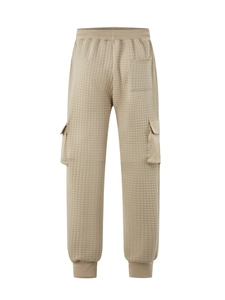 Detail of khaki quilted cargo pants showing grid texture and side tactical pockets
