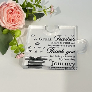 Macro shot of puzzle-shaped acrylic plaque with teacher appreciation quote and pink rose