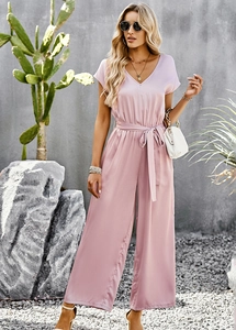 Detail of pink V-neck short sleeve jumpsuit featuring waist tie and flowy wide-leg pants