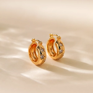 Detail of gold-plated hoop earrings featuring star cutouts with sparkling cubic zirconia