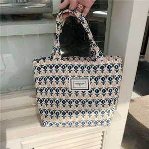 Detail of corduroy lunch bag featuring blue and pink tulip patterns and logo patch