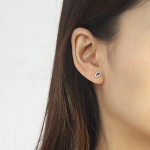 Close-up of S925 sterling silver evil eye stud earring with blue stone on ear