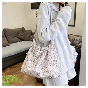 Detail of floral canvas shoulder bag with red patterns and drawstring closure mechanism