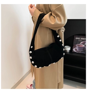 Close-up of black suede shoulder bag with silver rivet details and crescent shape design