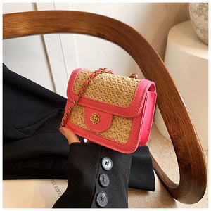 Close-up of pink woven flap bag with golden flower clasp and metal chain strap