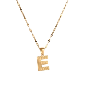 Macro detail of gold letter E pendant featuring delicate dotted texture on a chain