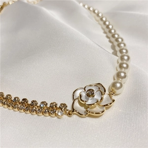 Détail du pendentif fleur avec chaîne en perles et strass sur fond de satin blanc