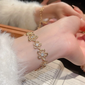 Close-up of a gold floral bracelet with sparkling zircons on a model's wrist