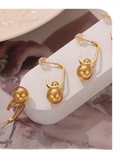 Detailed macro view of U-shaped gold earrings with dual polished spheres on a white display