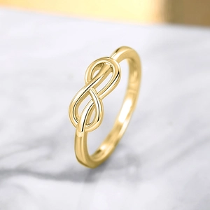Detail macro-opname van een gouden infinity ring op grijs marmeren ondergrond