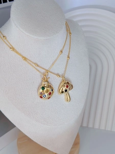 Detail of gold-plated ladybug and mushroom pendants with colorful gemstones on a chain