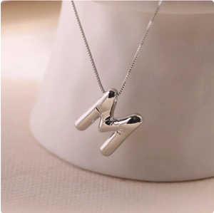 Detailed macro view of 3D bubble letter M pendant with a polished silver finish on box chain