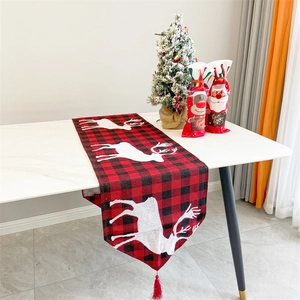 Detail of red and black buffalo plaid Christmas table runner with white reindeer silhouettes