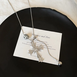 Detail of cross pendant necklace with zircon stones, spotted bead and metal ball charms