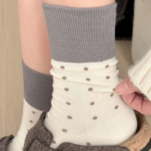 Retro grey and beige polka dot crew socks with ribbed cuffs on wooden floor