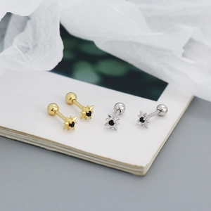 Macro shot of silver and gold star-shaped stud earrings with black gemstone accents