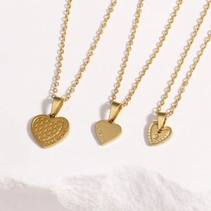 Three gold heart necklaces with Forever Love and Love You engravings on white texture
