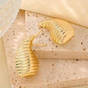 Close-up of textured golden teardrop earrings with elegant horizontal ridges on stone