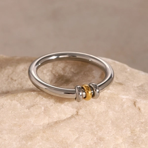 Macro view of minimalist stainless steel ring with three sliding gold and silver beads
