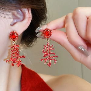 Detail of red rhinestone stud earrings featuring Chinese characters Xi and Le for luck