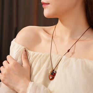 Detail of bohemian wax cord necklace featuring multi-colored beads and a red heart pendant