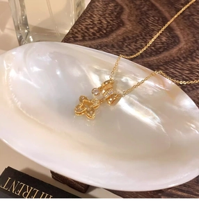 Detailed view of a gold flower pendant necklace with zircons on a white shell tray