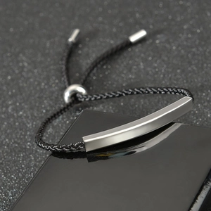 Macro detail of adjustable black woven cord bracelet with matte silver stainless steel bar