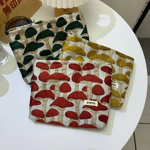 Detailed texture of jacquard mushroom cosmetic bags in red, yellow and green colors