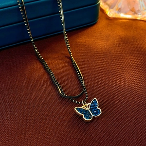 Detail of double-layer choker with golden butterfly pendant on red textured fabric