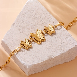 Matte gold butterfly charm bracelet on stone base with wave light shadows