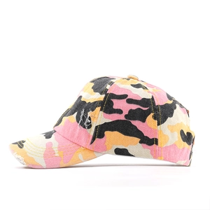 Detail view of pink and yellow camo ponytail baseball cap with distressed brim finish