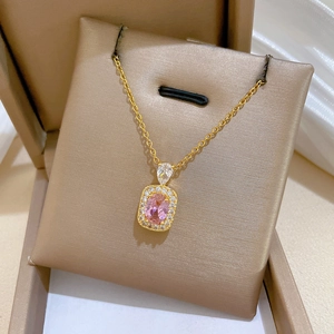 Close-up of pink oval gemstone pendant with diamond halo on golden chain jewelry box